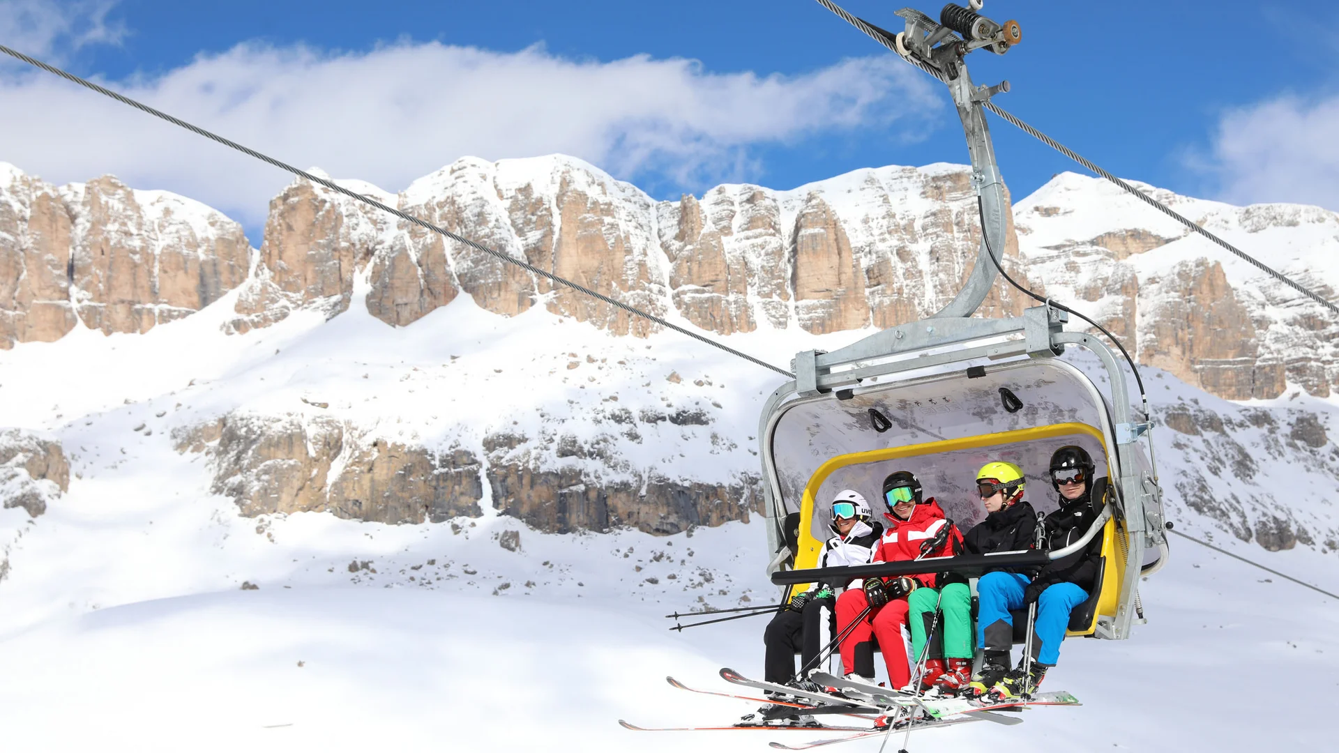 Bilder aus Arabba des Chalet Barbara Vier Skifahrer auf Sessellift vor schneebedeckten Bergen