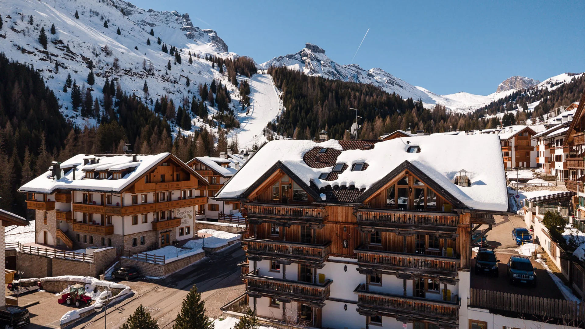 Bilder aus Arabba des Chalet Barbara Holzhäuser mit schneebedeckten Dächern in sonnigem Bergdorf