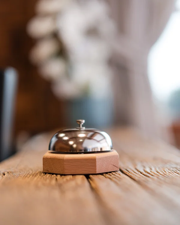 The story of our chalet in Arabba Metal reception bell on rustic wooden table