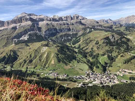 Panoramic view of a village among mountains and green meadows in the Dolomites