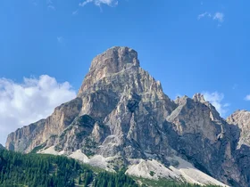 Rocky mountain with green forest and blue sky with few clouds
