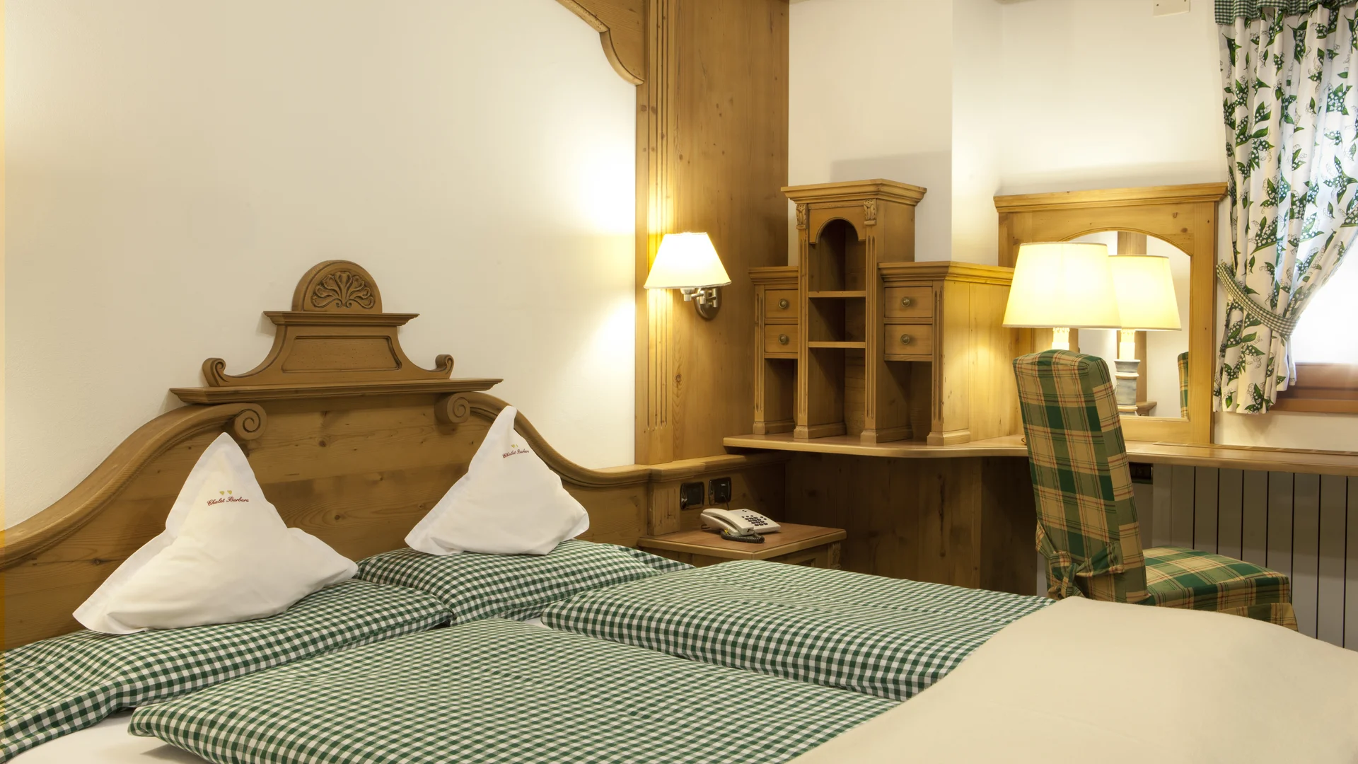 Bilder aus Arabba des Chalet Barbara Schlafzimmer mit Einzelbetten, Holzmöbeln und grün kariertem Stuhl