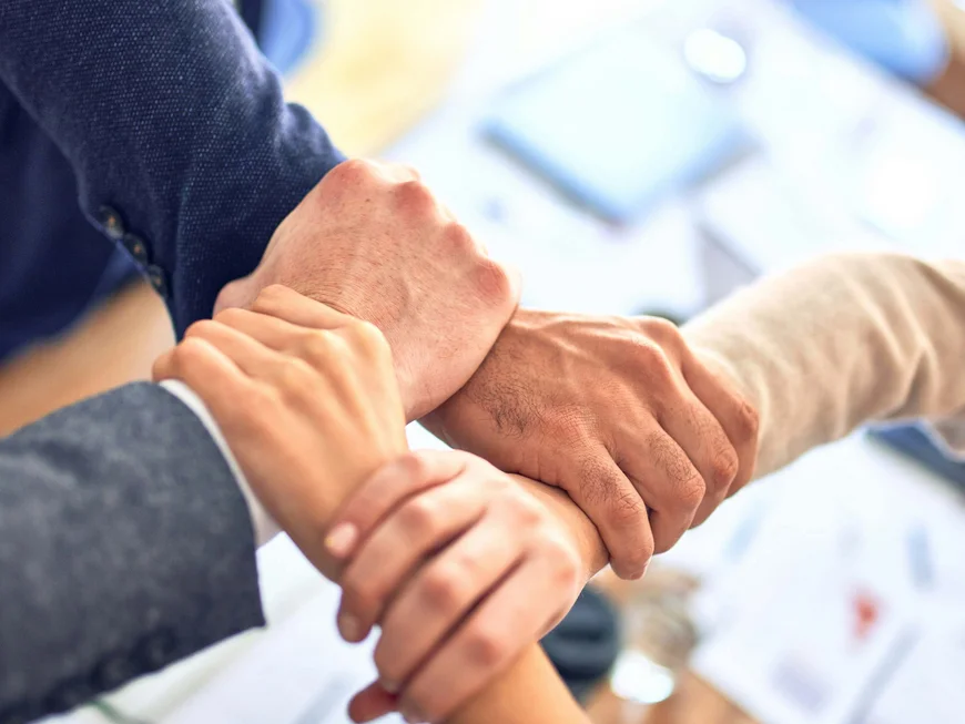 The story of our chalet in Arabba Four people holding each other's wrists in a teamwork gesture