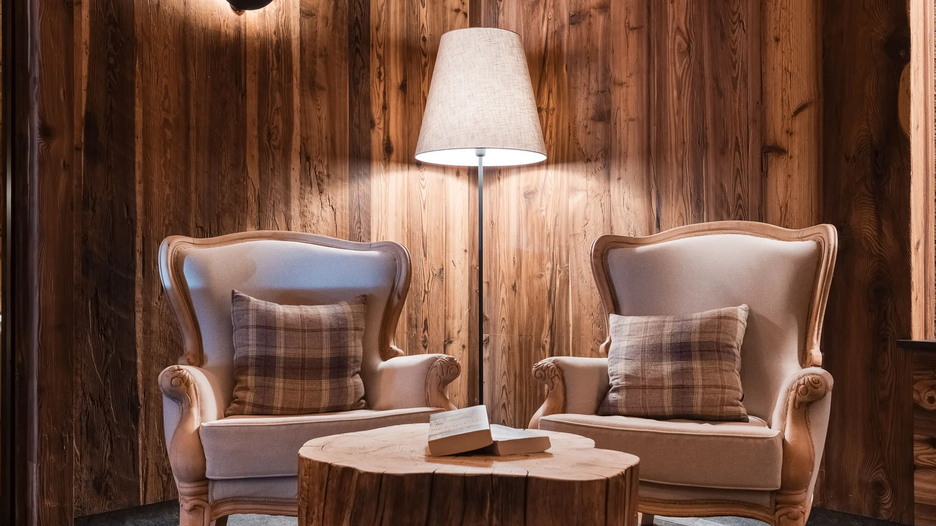 Two beige armchairs with plaid cushions and wooden table in rustic room