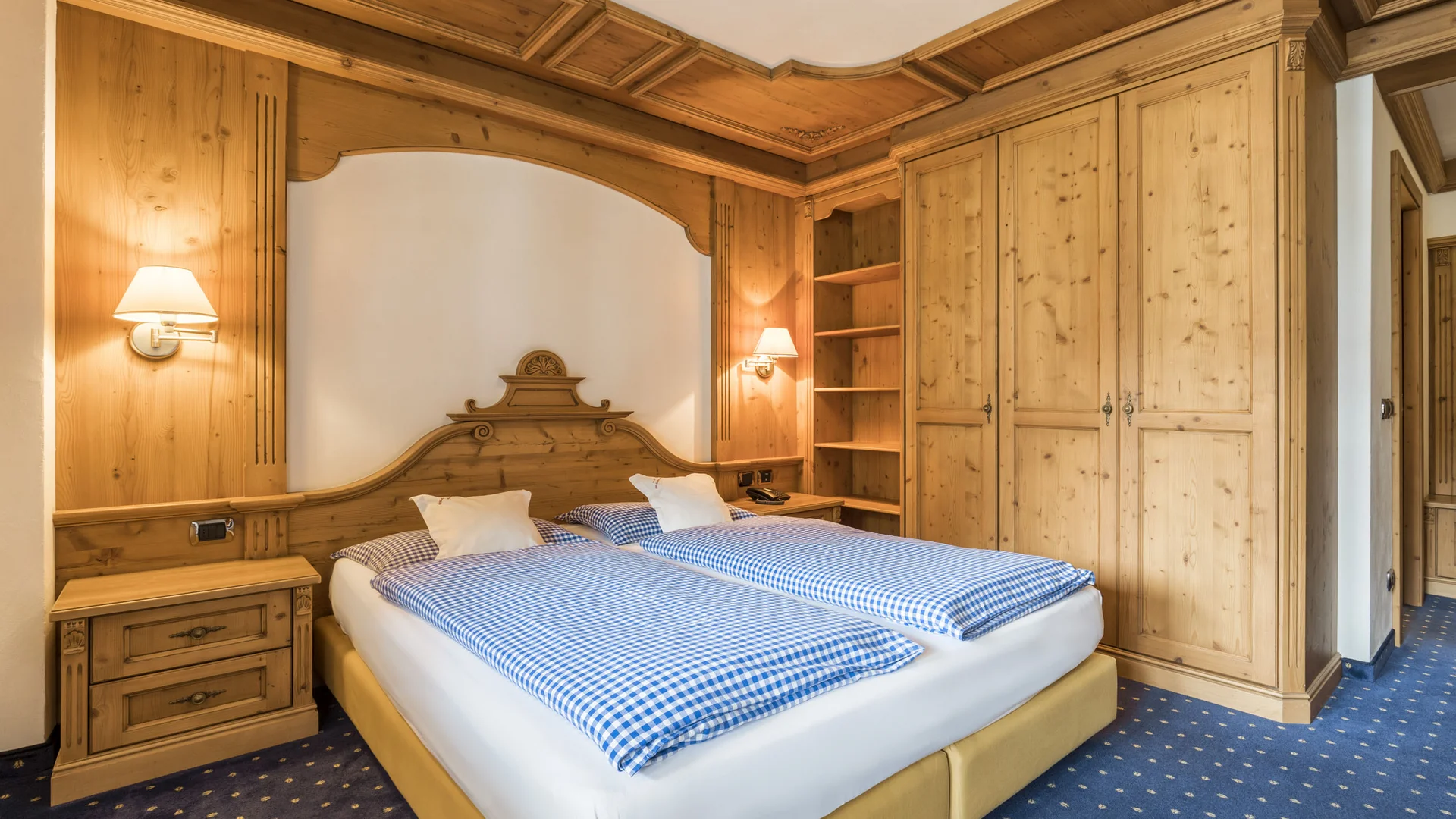 Bilder aus Arabba des Chalet Barbara Schlafzimmer mit Doppelbett, Holzkleiderschrank und Wandlampen