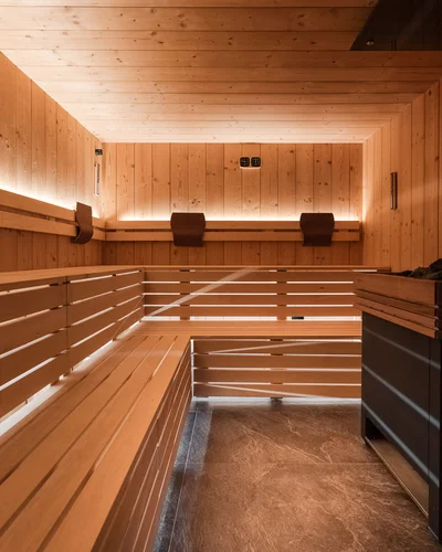 Dein Chalet-Hotel mit Wellness in den Dolomiten Innenraum einer Holzsauna mit Bank und sanfter Beleuchtung