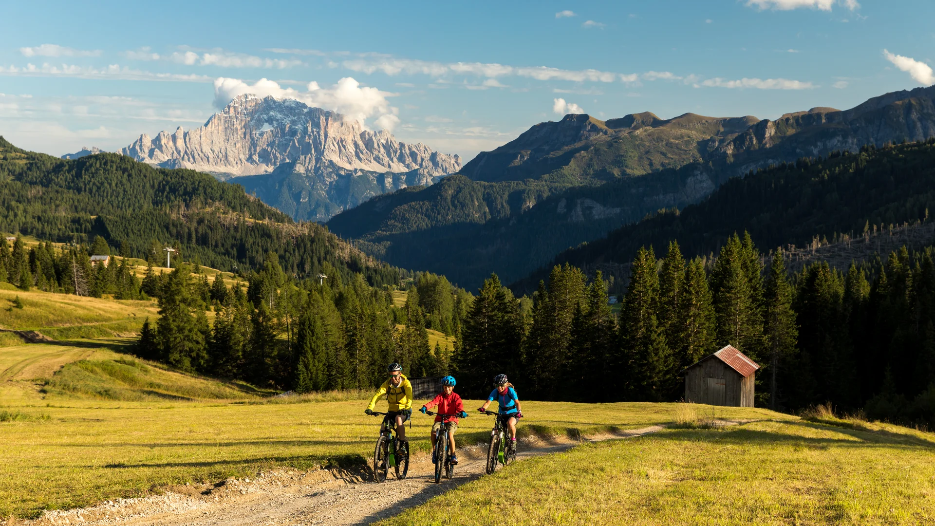 Bilder aus Arabba des Chalet Barbara Drei Personen fahren Mountainbike auf einem Bergweg mit Alpenlandschaft