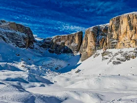 Snow-covered rocky mountains under a blue sky with scattered clouds