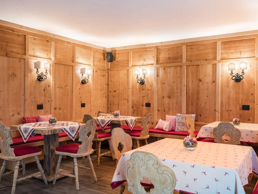 Rustikaler Speiseraum mit Holztischen, Stühlen und Holzvertäfelung