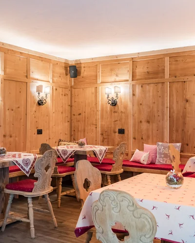 Rustic dining room with wooden tables, chairs, and wood-paneled walls