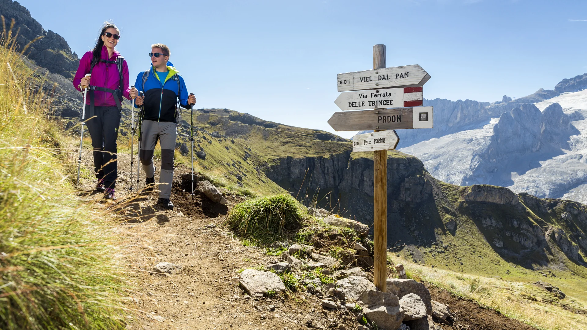 Bilder aus Arabba des Chalet Barbara Paar wandert auf Bergweg mit Wegweisern bei klarem Himmel