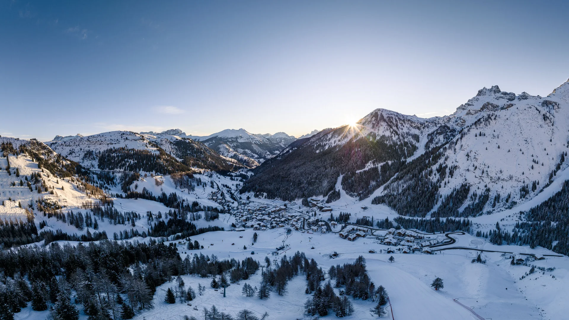 Winter landscape with village in snowy mountains at sunset