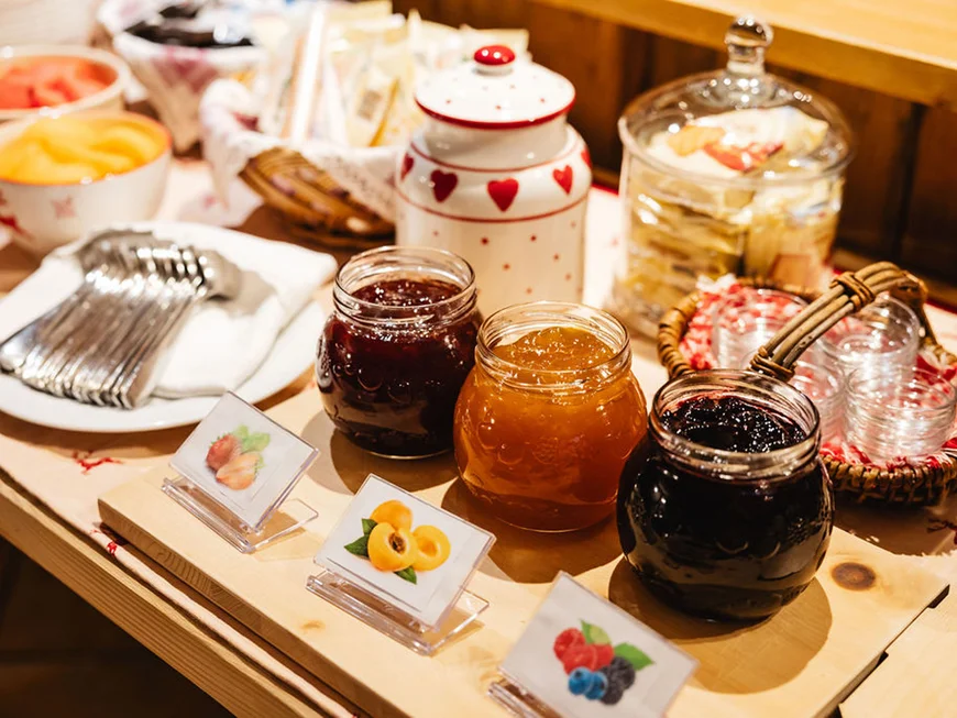 The story of our chalet in Arabba Jars of assorted jams with labels and cutlery on a wooden table