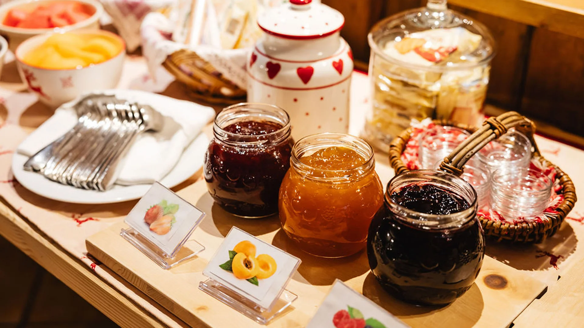 Bilder aus Arabba des Chalet Barbara Gläser mit verschiedenen Marmeladen und Besteck auf einem Holztisch