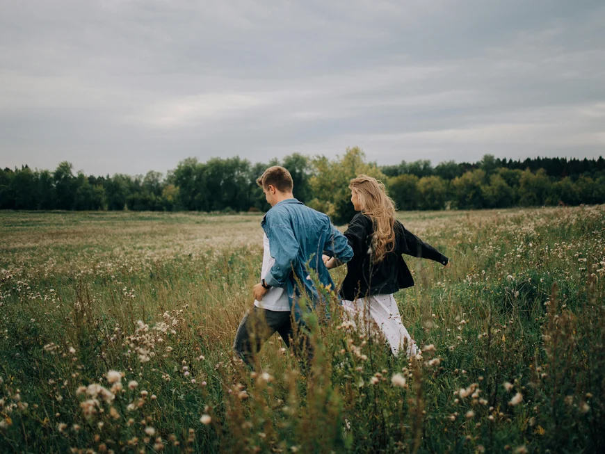 The story of our chalet in Arabba Couple walking hand in hand through a flowering field under a cloudy sky