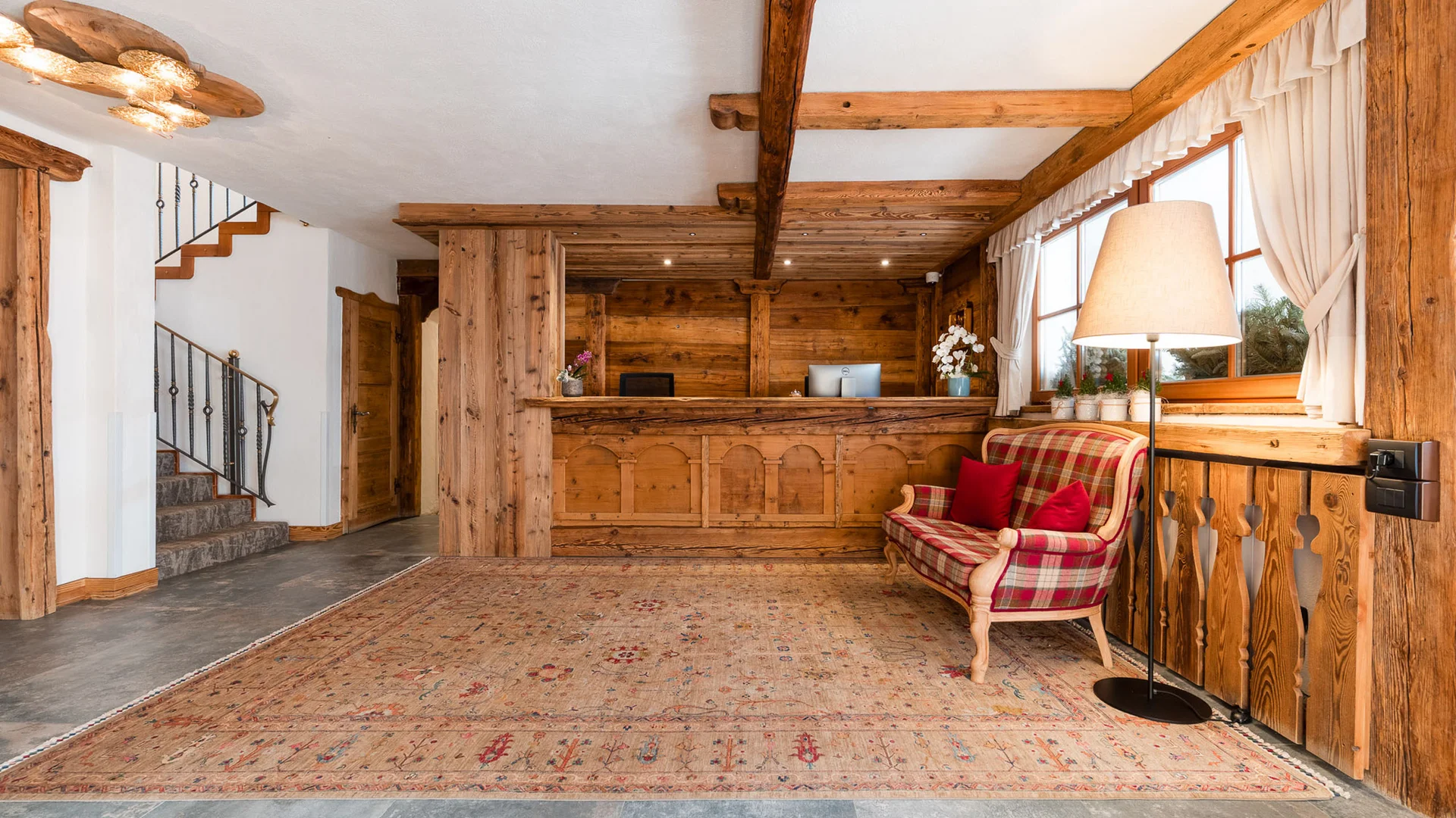 Bilder aus Arabba des Chalet Barbara Holzrezeption mit kariertem Sofa und Stehlampe in rustikalem Raum