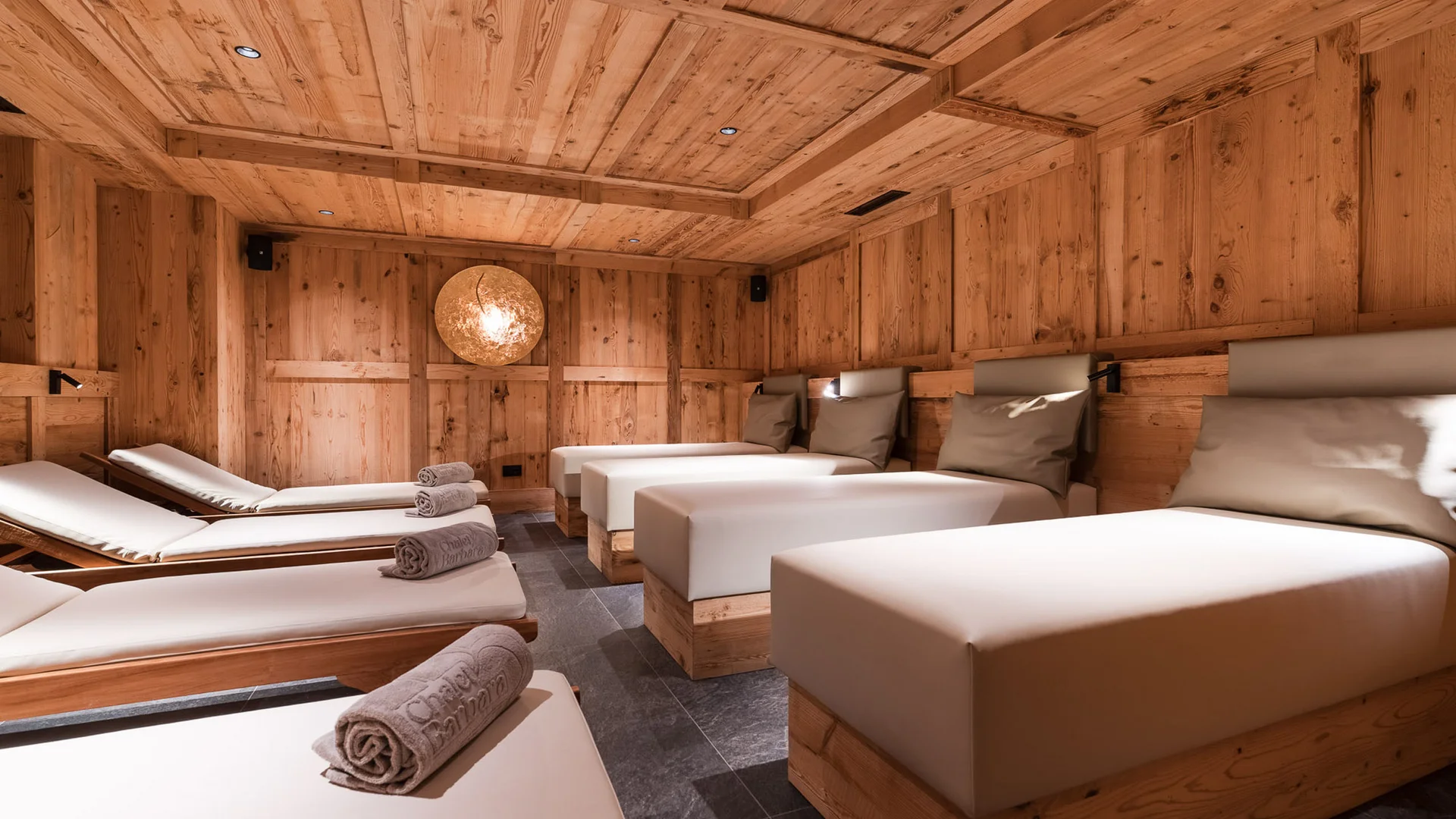 The story of our chalet in Arabba Wood-paneled relaxation room with cushioned loungers and rolled towels