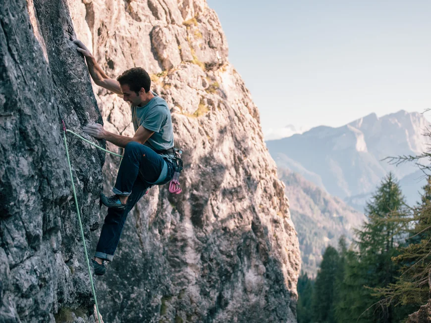 Man rock climbing on a mountain with alpine landscape in the background