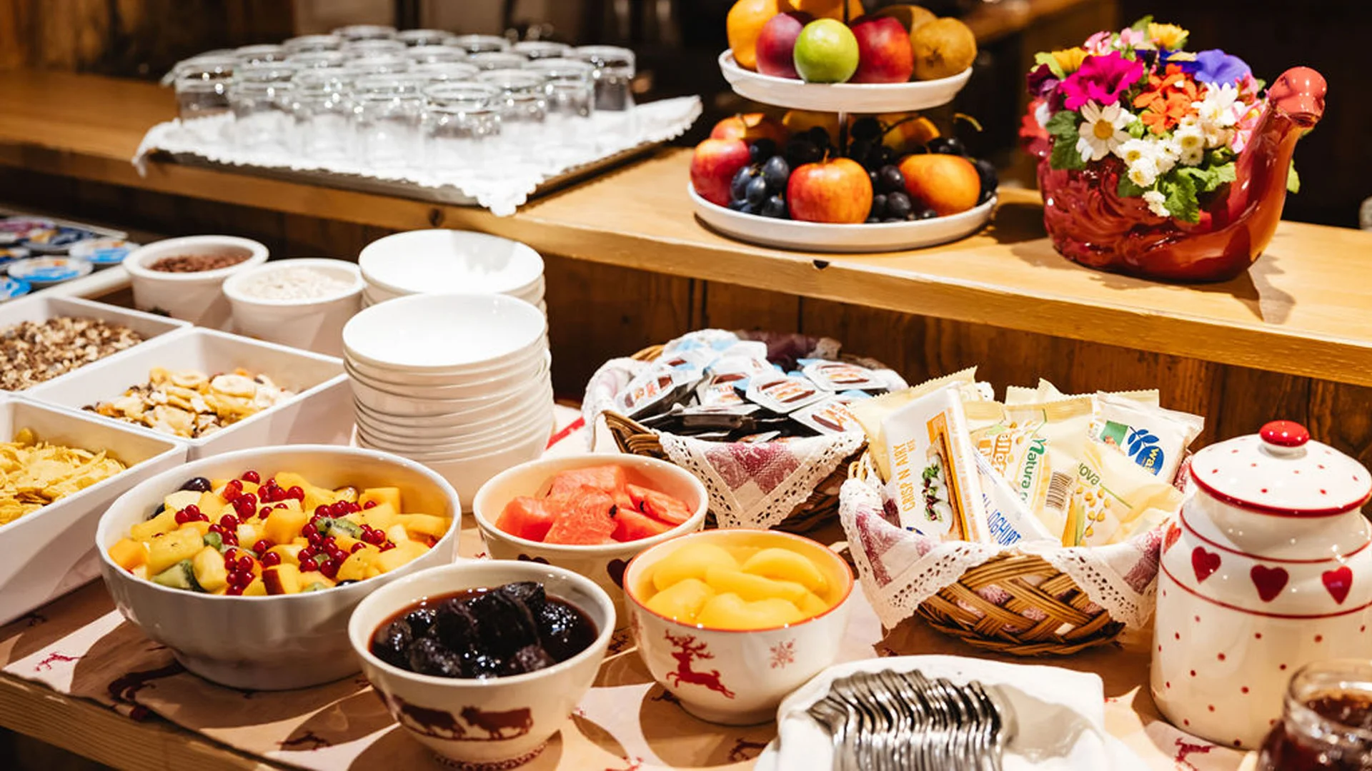 Buffet mit frischem Obst, Müsli, Marmeladen und Gläsern auf Holztisch
