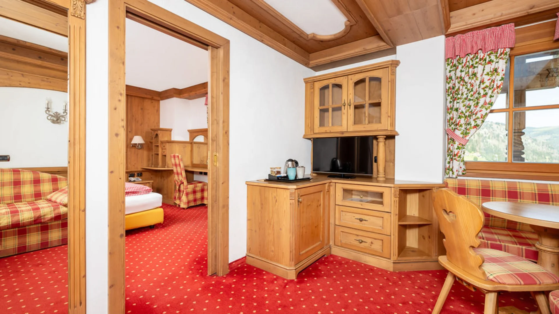Bilder aus Arabba des Chalet Barbara Innenraum eines Hotelzimmers mit Holzmöbeln und rotem Teppich
