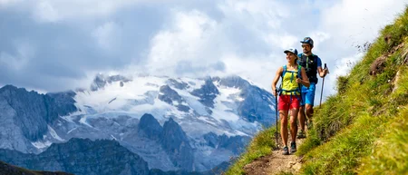 Zwei Wanderer auf Bergpfad mit Blick auf schneebedeckte Berge