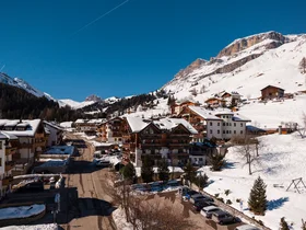 Snow-covered mountain village with wooden houses and sunny street