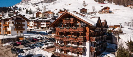 Wooden hotel with flowered balconies and snowy mountains in the background