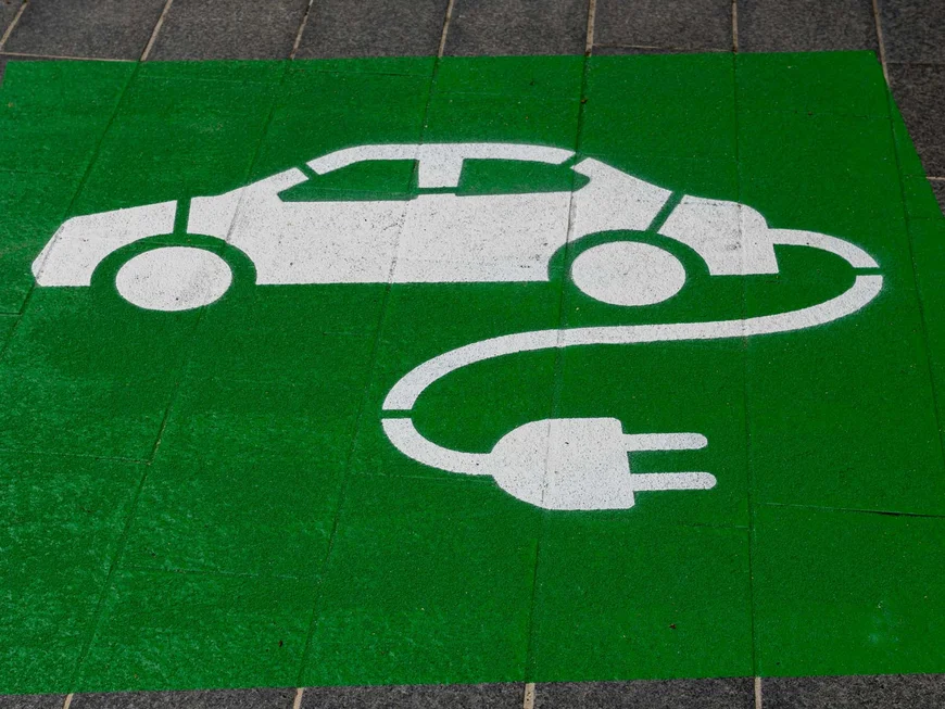 The story of our chalet in Arabba White electric car symbol with plug on green background on sidewalk