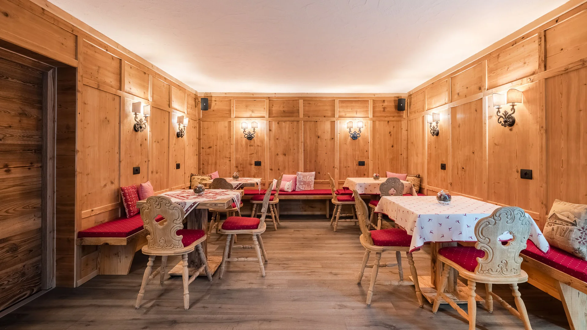 Bilder aus Arabba des Chalet Barbara Esszimmer mit Holzwänden, roten Stühlen und gedeckten Tischen