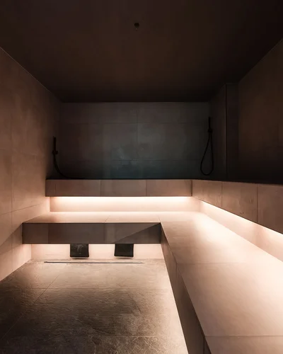 Dein Chalet-Hotel mit Wellness in den Dolomiten Innenraum einer modernen Sauna mit beleuchtetem Sitzbereich und Wandduschen