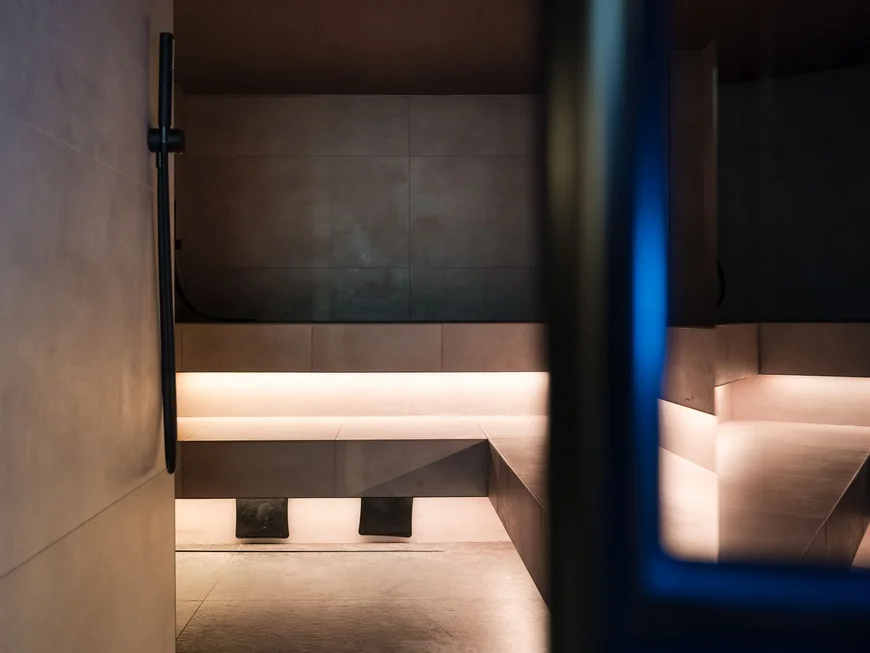 Interno di una sauna moderna con panchine illuminate e pareti scure