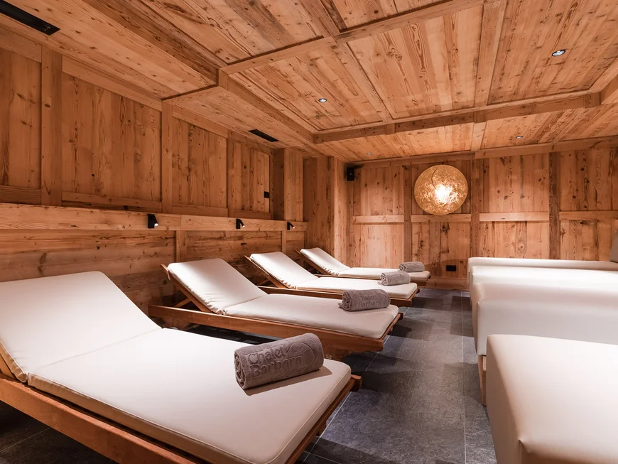 Wood-paneled relaxation room with cushioned loungers and rolled towels