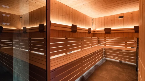 Accessibility Interior of a wooden sauna with warm lighting and corner bench seating