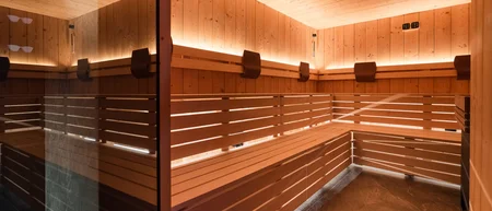 Innenraum einer Sauna aus Holz mit warmer Beleuchtung und Eckbank