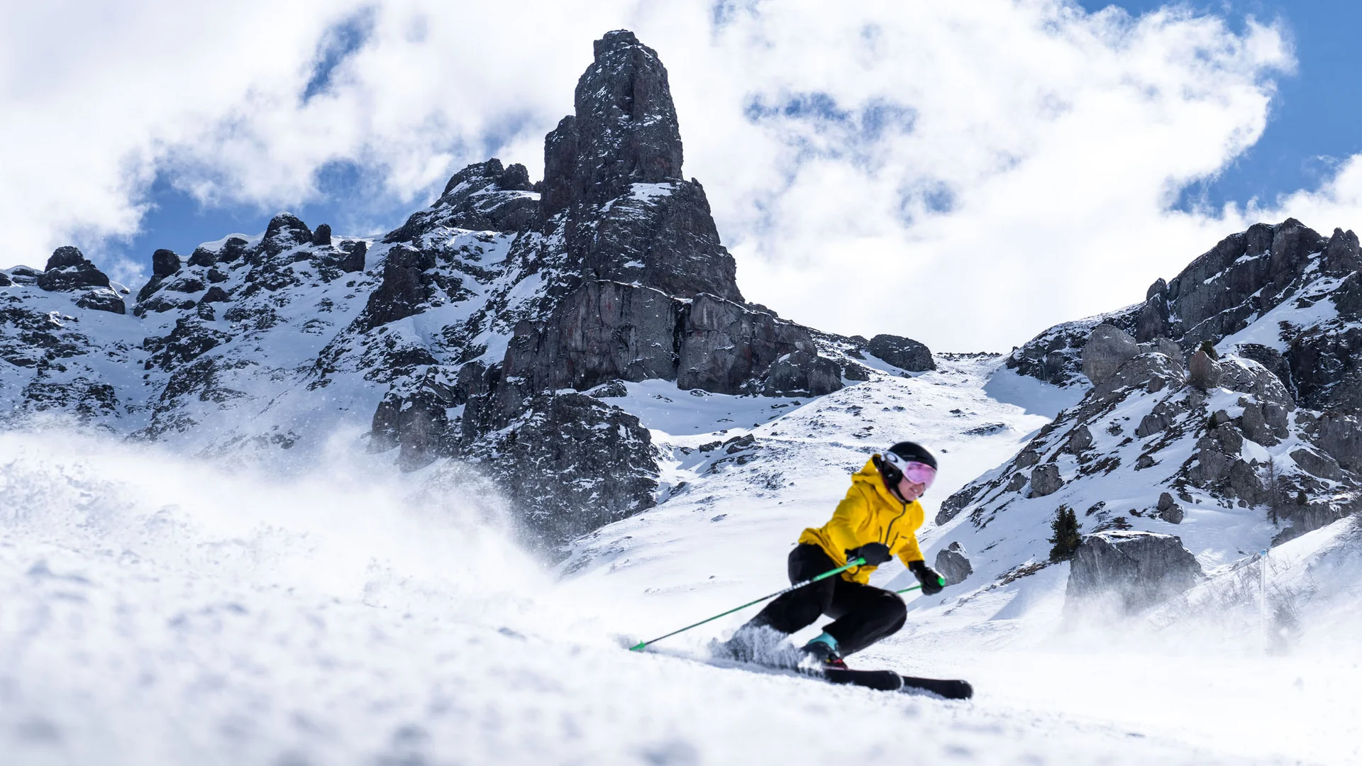 Bilder aus Arabba des Chalet Barbara Skifahrer mit gelber Jacke auf verschneiter Piste vor felsigen Bergen