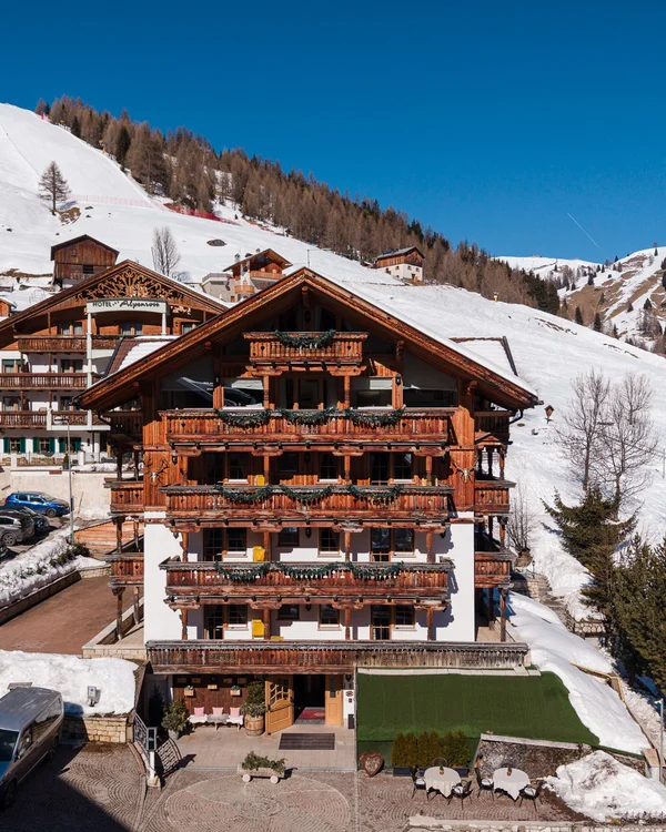 The story of our chalet in Arabba Wooden hotel with balconies in snowy mountain landscape under blue sky