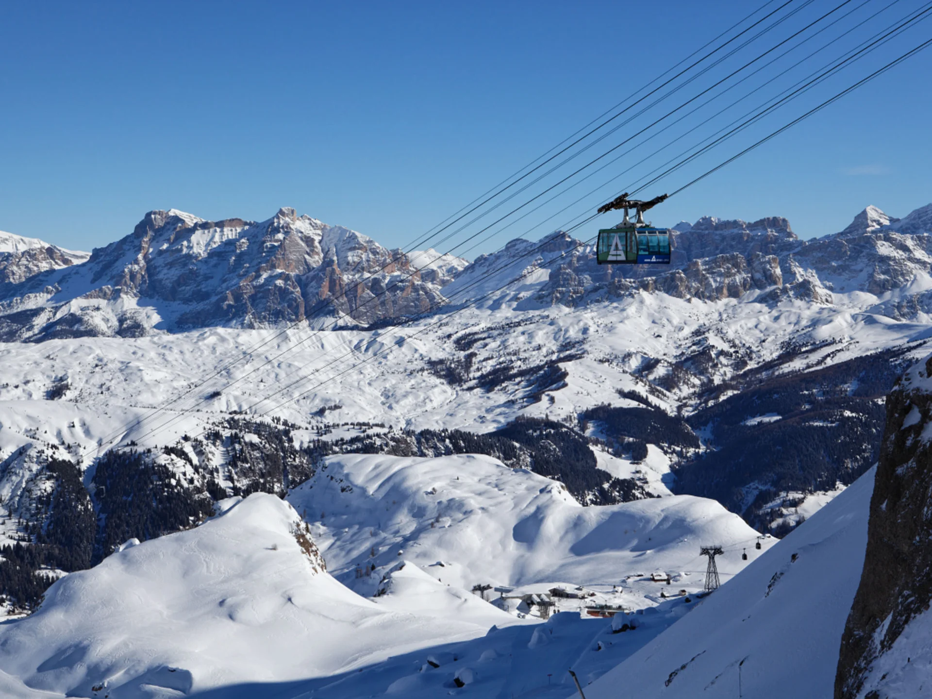 Cable car over snowy mountains under clear blue sky