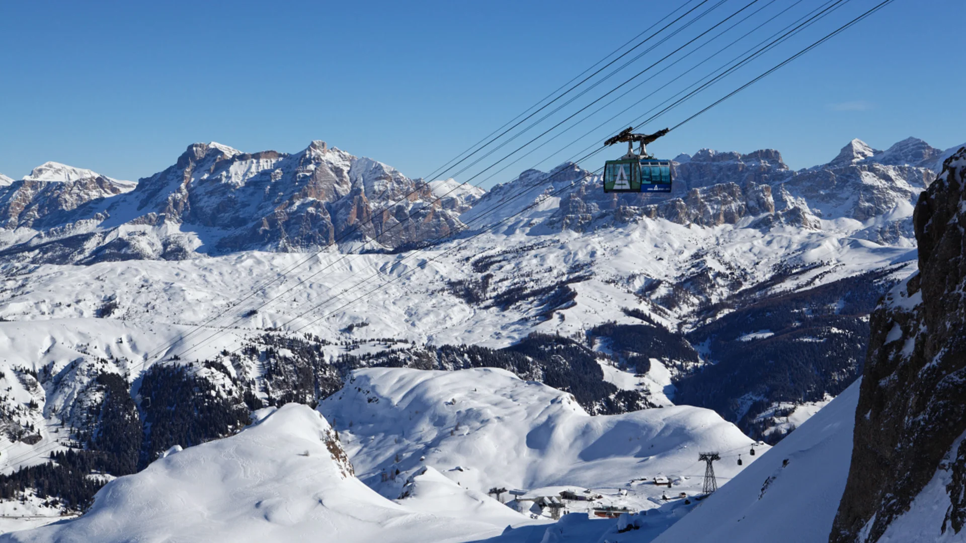Bilder aus Arabba des Chalet Barbara Seilbahn vor schneebedeckten Bergen unter klarem blauem Himmel