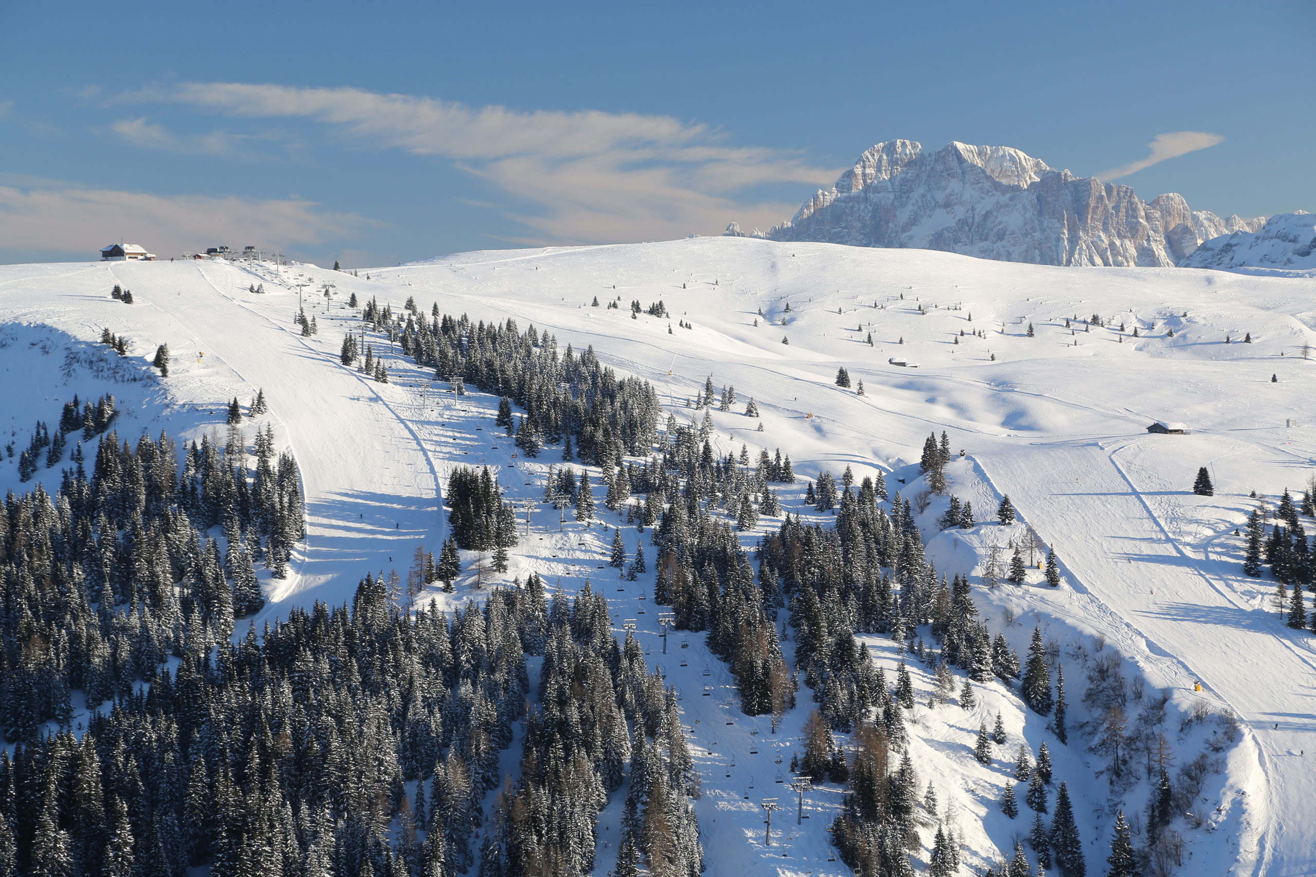 Snow-covered ski slope with trees and mountains in the background